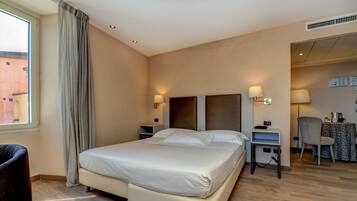 A hotel room with a large bed, bedside tables, a chair, and a desk with a lamp.