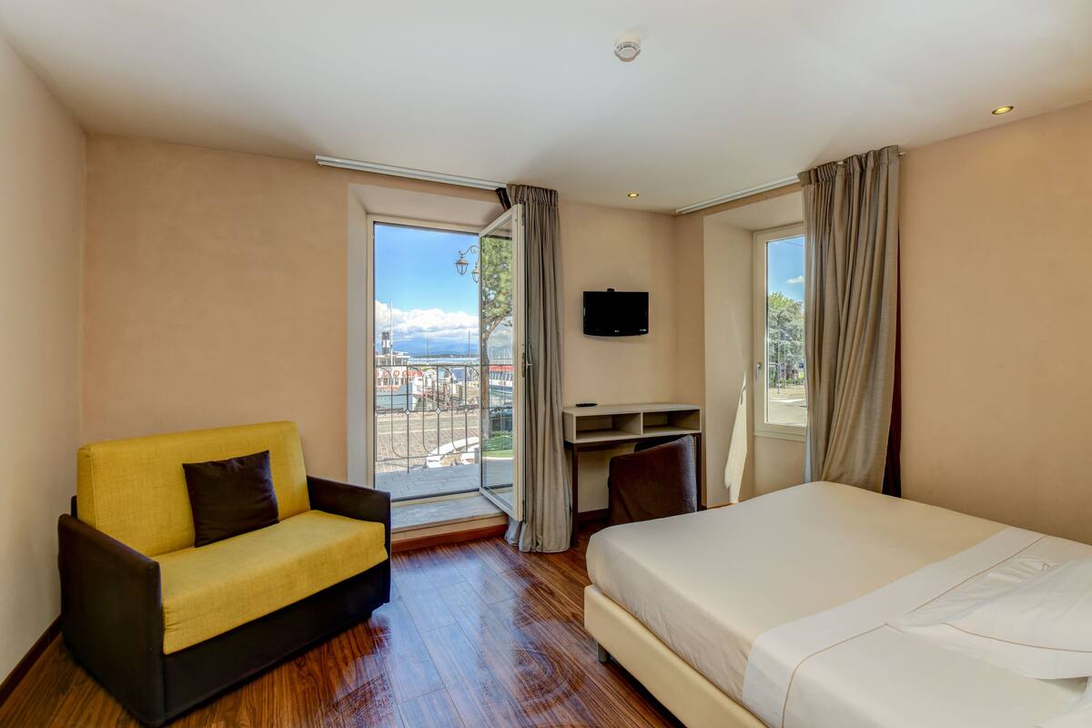 A hotel room with a bed, a sofa, a desk, and a TV.