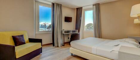 A hotel room with a bed, a sofa, a desk, and a TV.