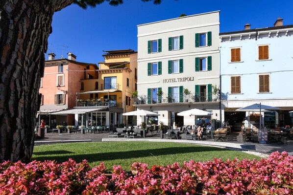 A hotel with outdoor seating and a garden. - Hotel Tripoli (Desenzano del Garda)