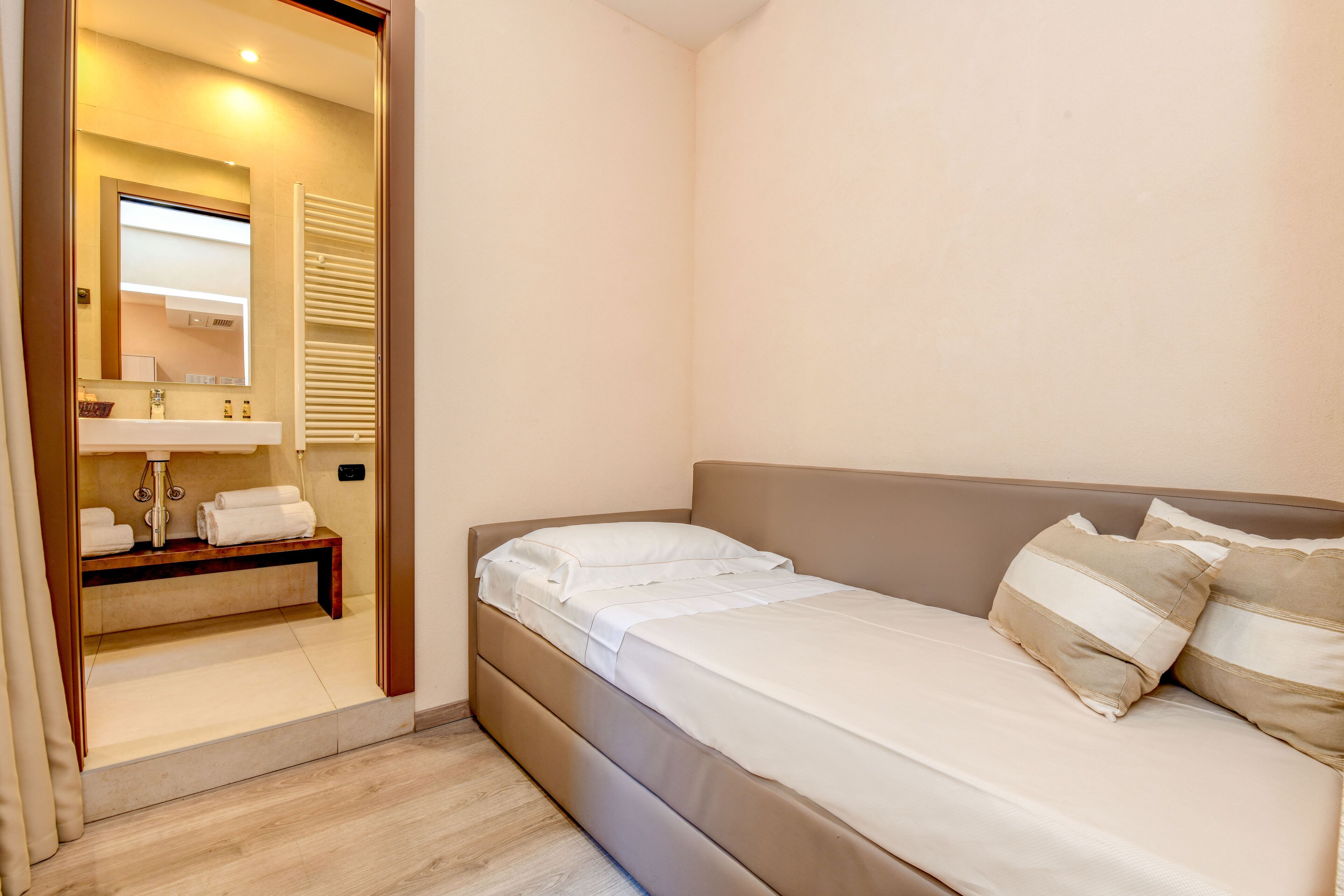 Un dormitorio con cama, mesita de noche y espejo.