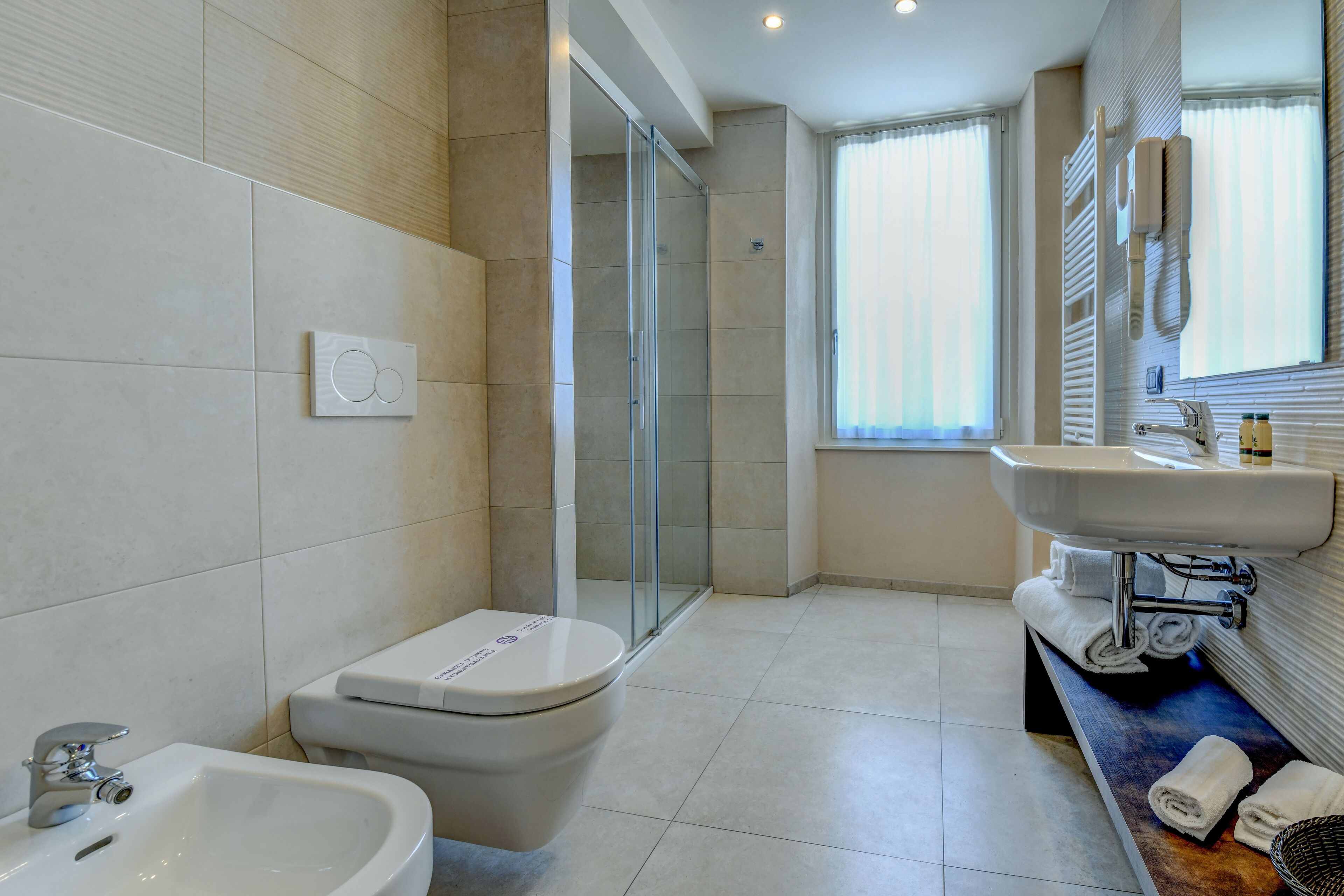 Une salle de bain moderne équipée d’une douche, de toilettes, d’un bidet et d’un lavabo.