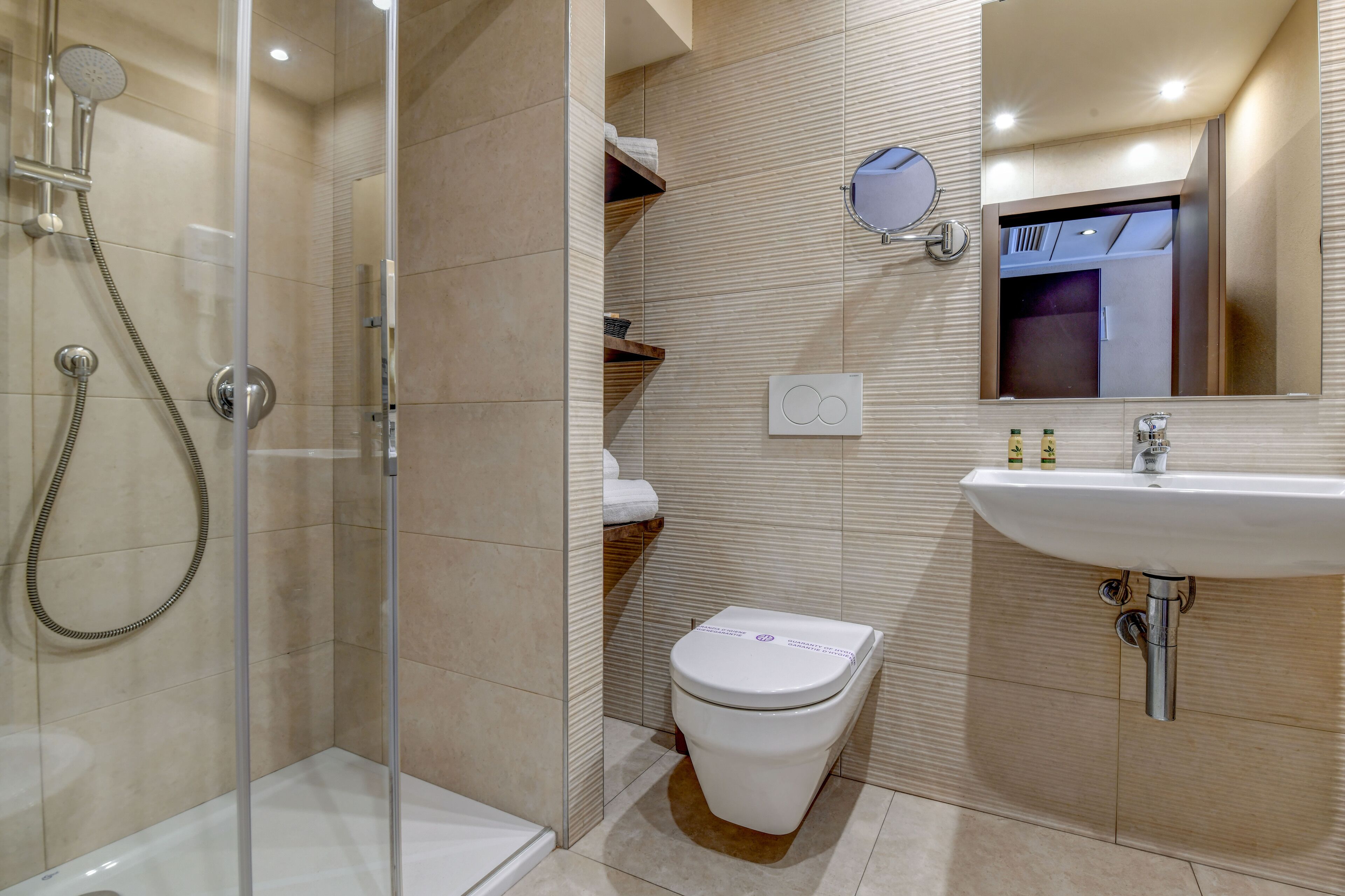 A modern bathroom with a glass-enclosed shower, a toilet, and a sink with a mirror above it.