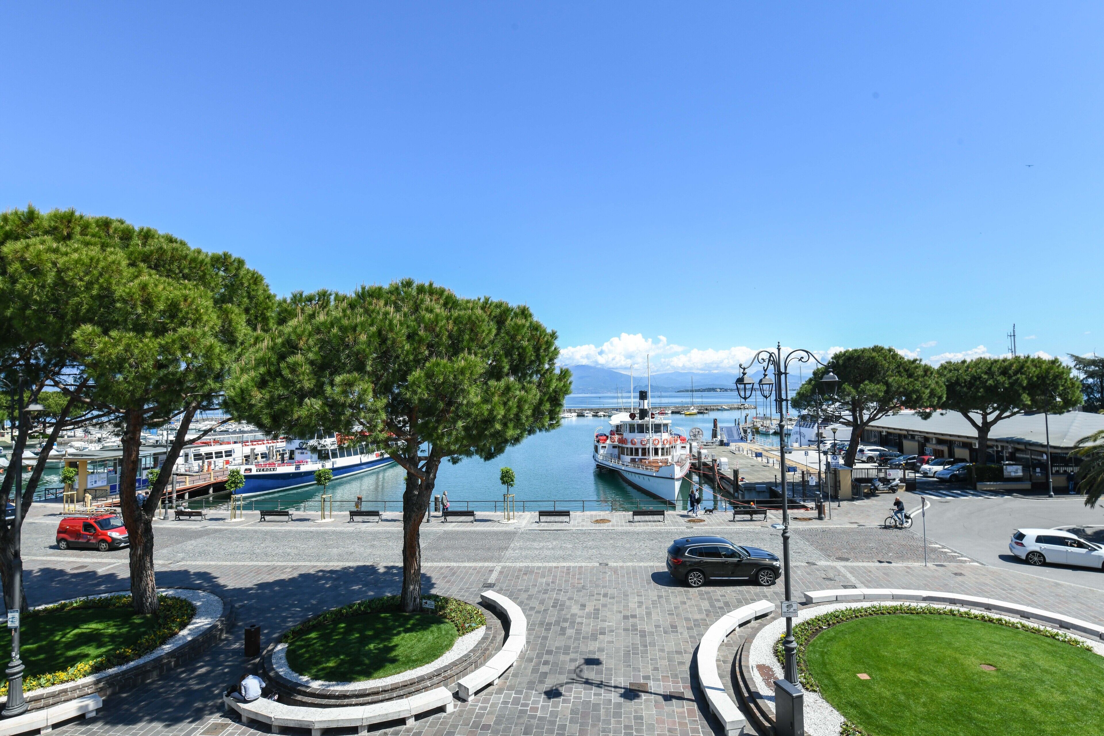 A waterfront promenade with trees, benches, and a boat dock.