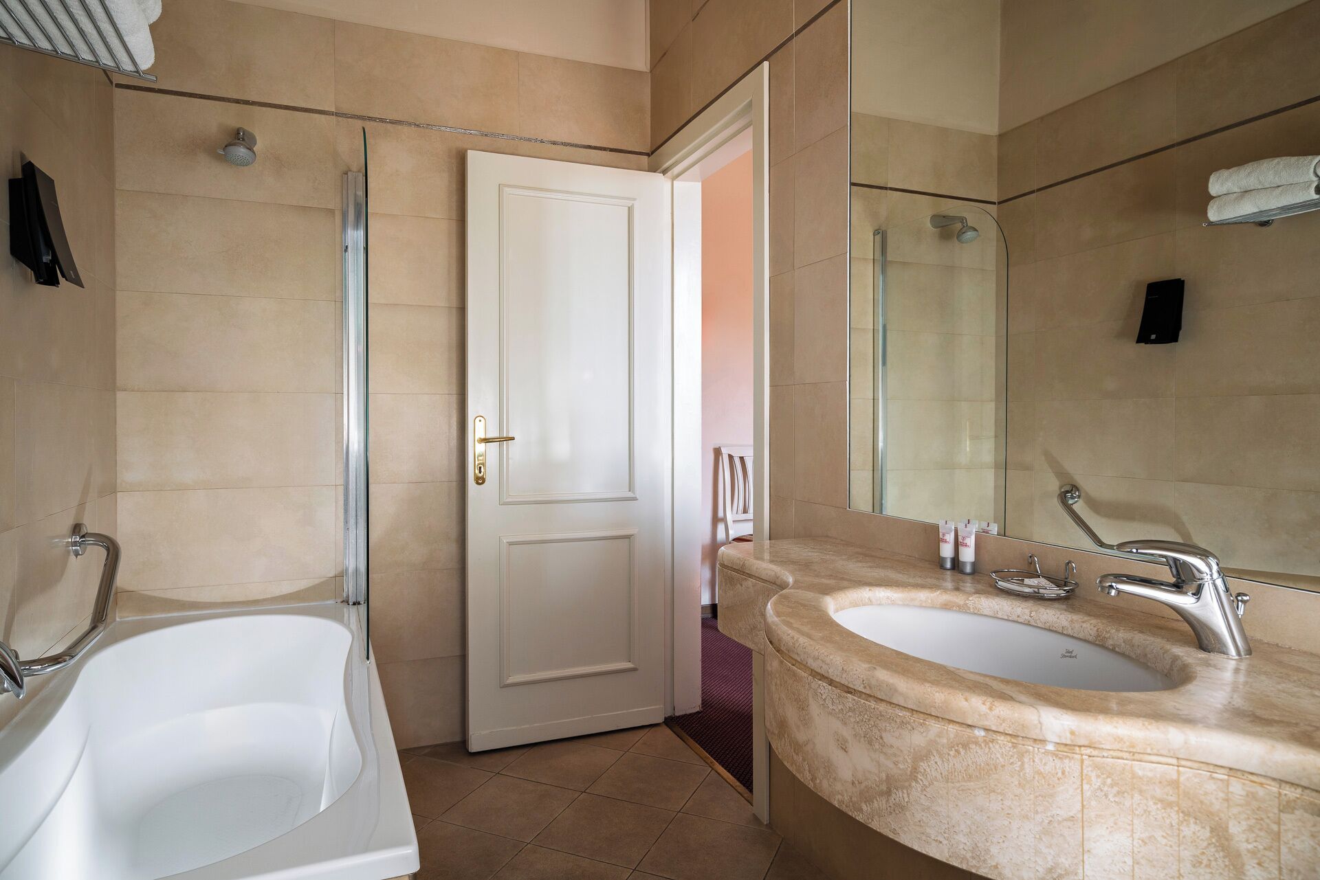 A bathroom with a bathtub, a shower, and a sink with a large mirror.