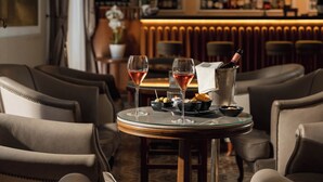 A bar area with two glasses of rosé wine on a round table, a bottle of champagne, olives, and snacks. - Ercolini E Savi (Montecatini Terme)