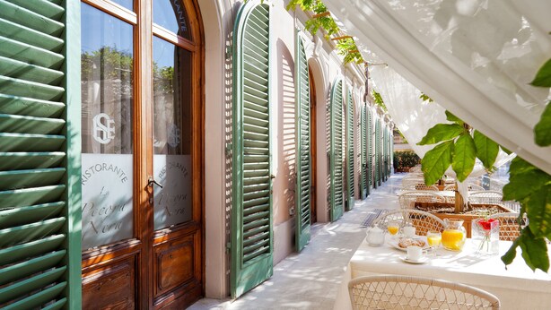 A restaurant with outdoor seating, wooden shutters, and a tiled floor. - Ercolini E Savi (Montecatini Terme)