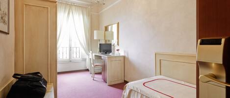 A hotel room with a bed, desk, chair, and a television.
