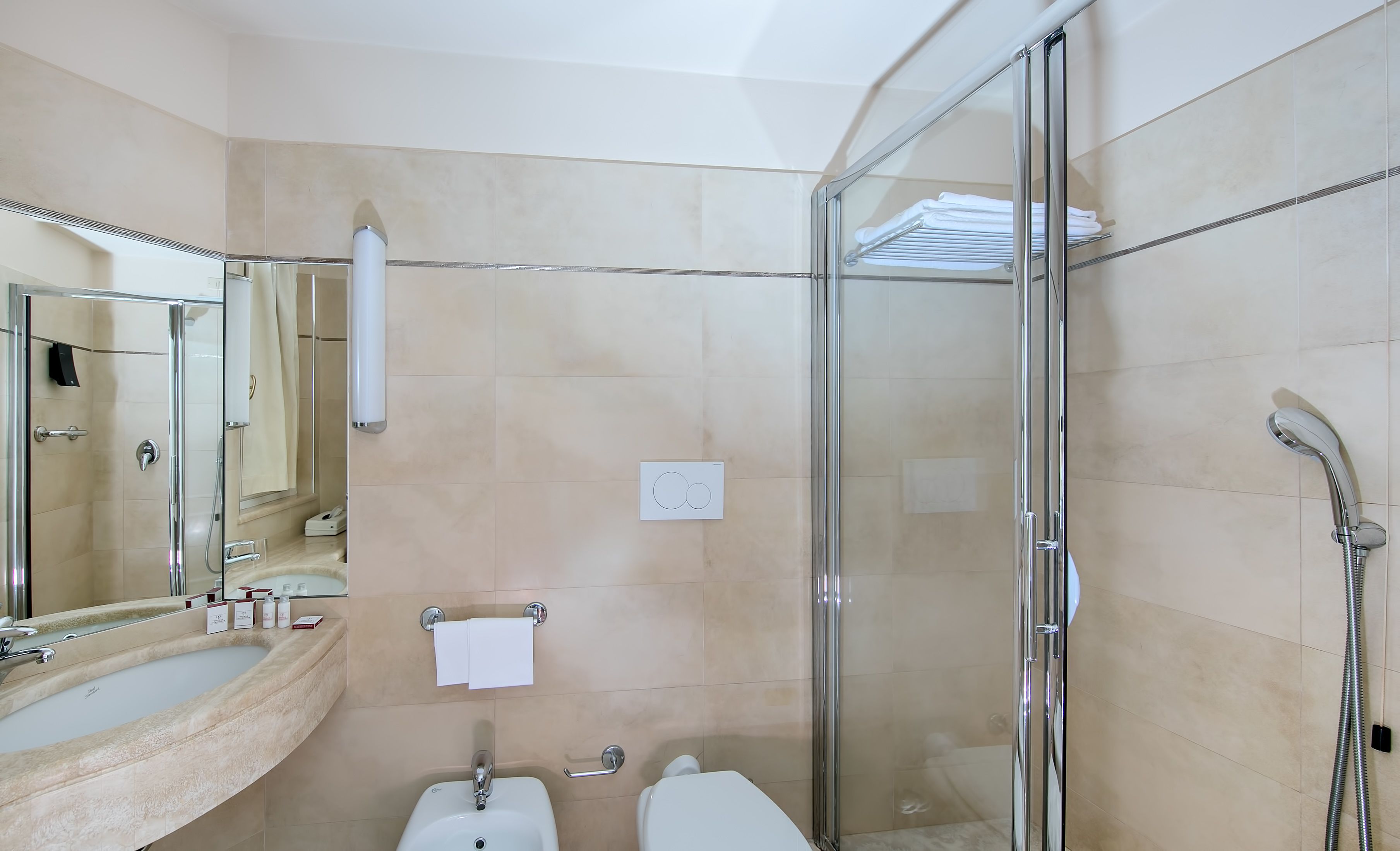 Un baño moderno con ducha de vidrio, lavamanos con tocador y un inodoro.