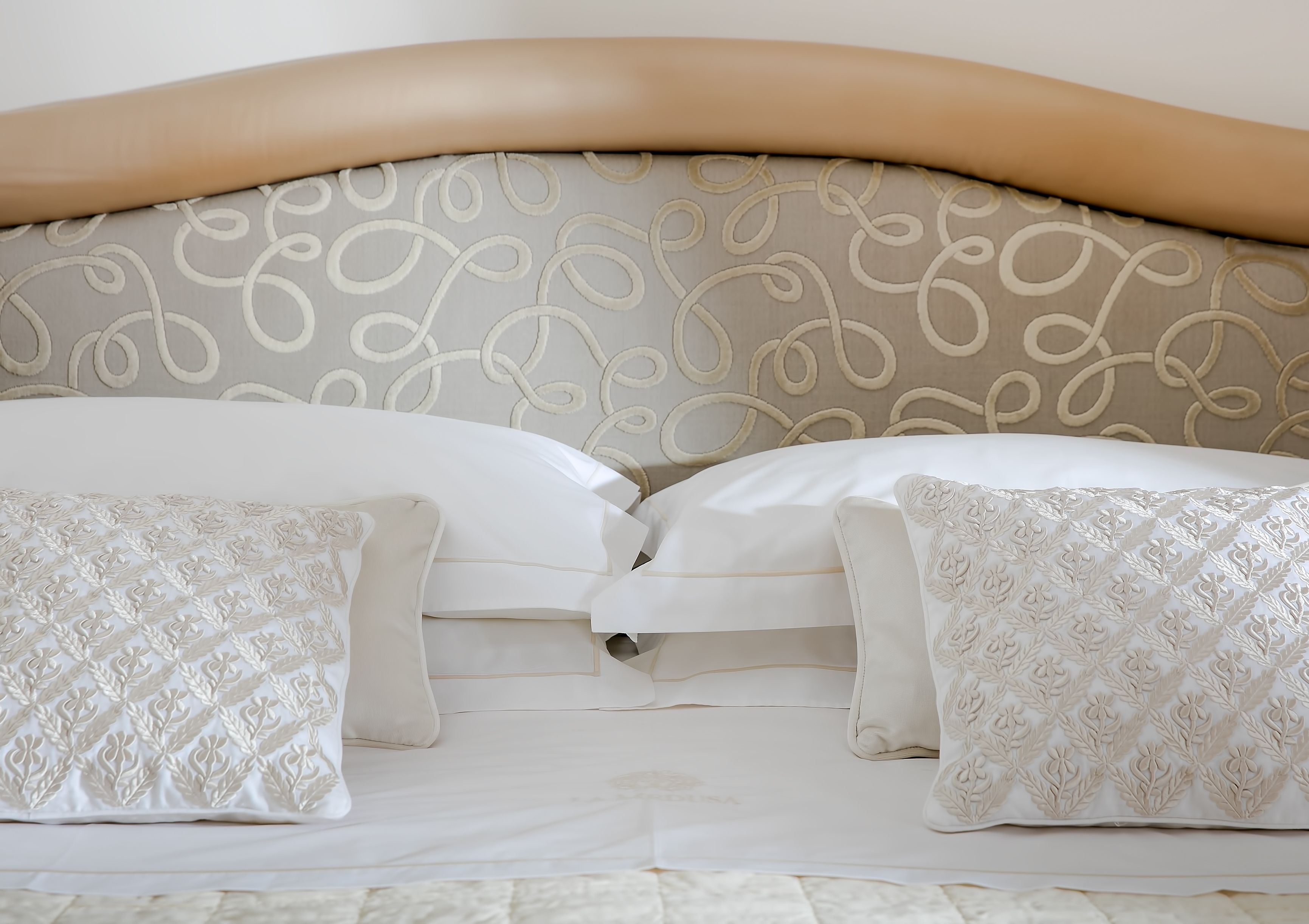 A bed with a beige headboard and white bedding.