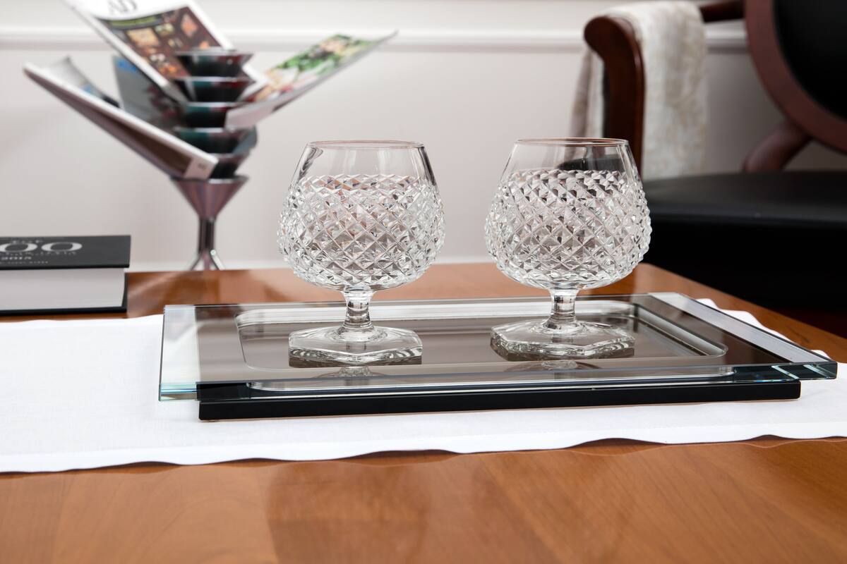 Two crystal glasses on a tray with a magazine and a book in the background.