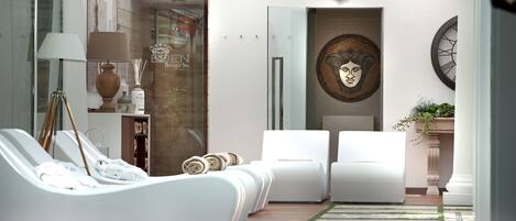 A modern spa area with a glass-enclosed pool, white lounge chairs, a large wall clock, and a decorative wall piece.
