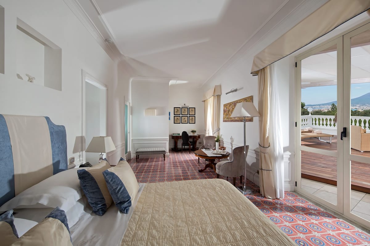 A hotel room with a bed, a desk, and a view of the city.