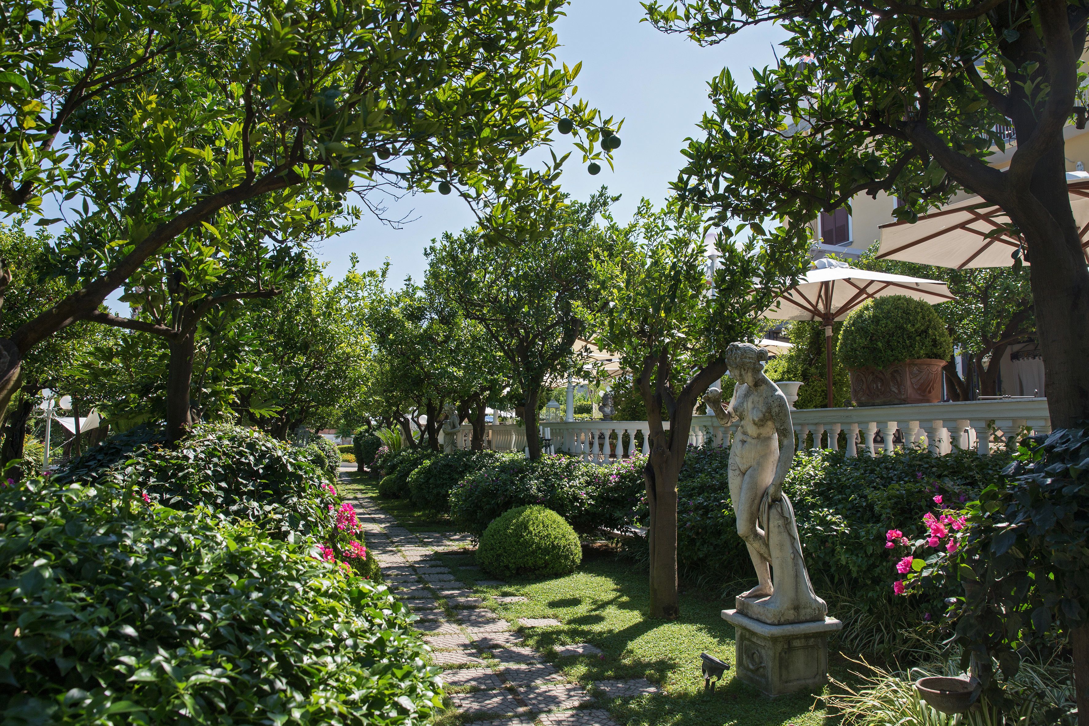 Un jardin agrémenté d’une statue, d’un chemin pavé et d’une végétation luxuriante.
