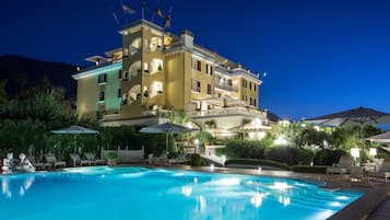 Relax by the pool surrounded by lush greenery and comfortable lounge chairs.