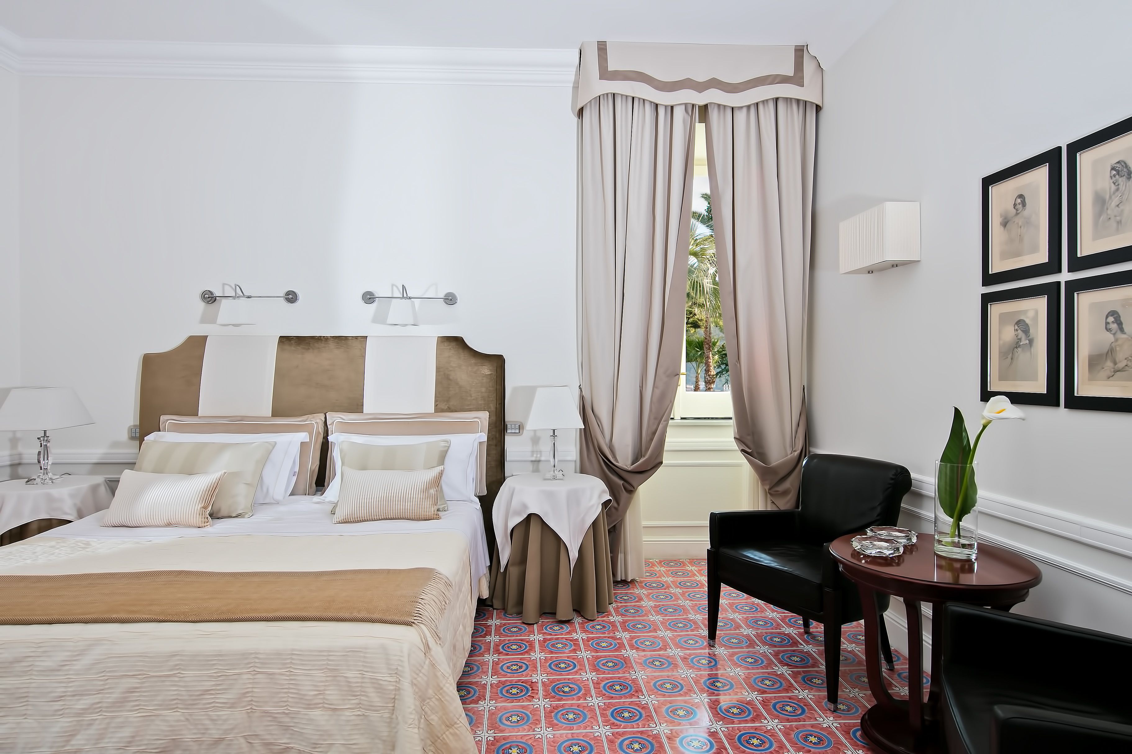 Quarto de hotel com uma cama grande, uma mesa pequena com um vaso e uma cadeira.