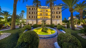 A hotel with a central fountain, surrounded by well-manicured gardens and palm trees. - La Medusa Dimora di Charme (Castellammare di Stabia)