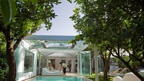 A modern glass-enclosed pool area with a clear view of the surrounding garden and a person tending to the pool. - La Medusa Dimora di Charme (Castellammare di Stabia)
