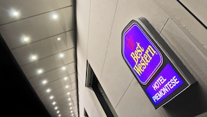 Une enseigne d’hôtel portant le nom « Best Western Hotel Piemontese », sur un bâtiment moderne doté d’un sol carrelé et d’un éclairage encastré.