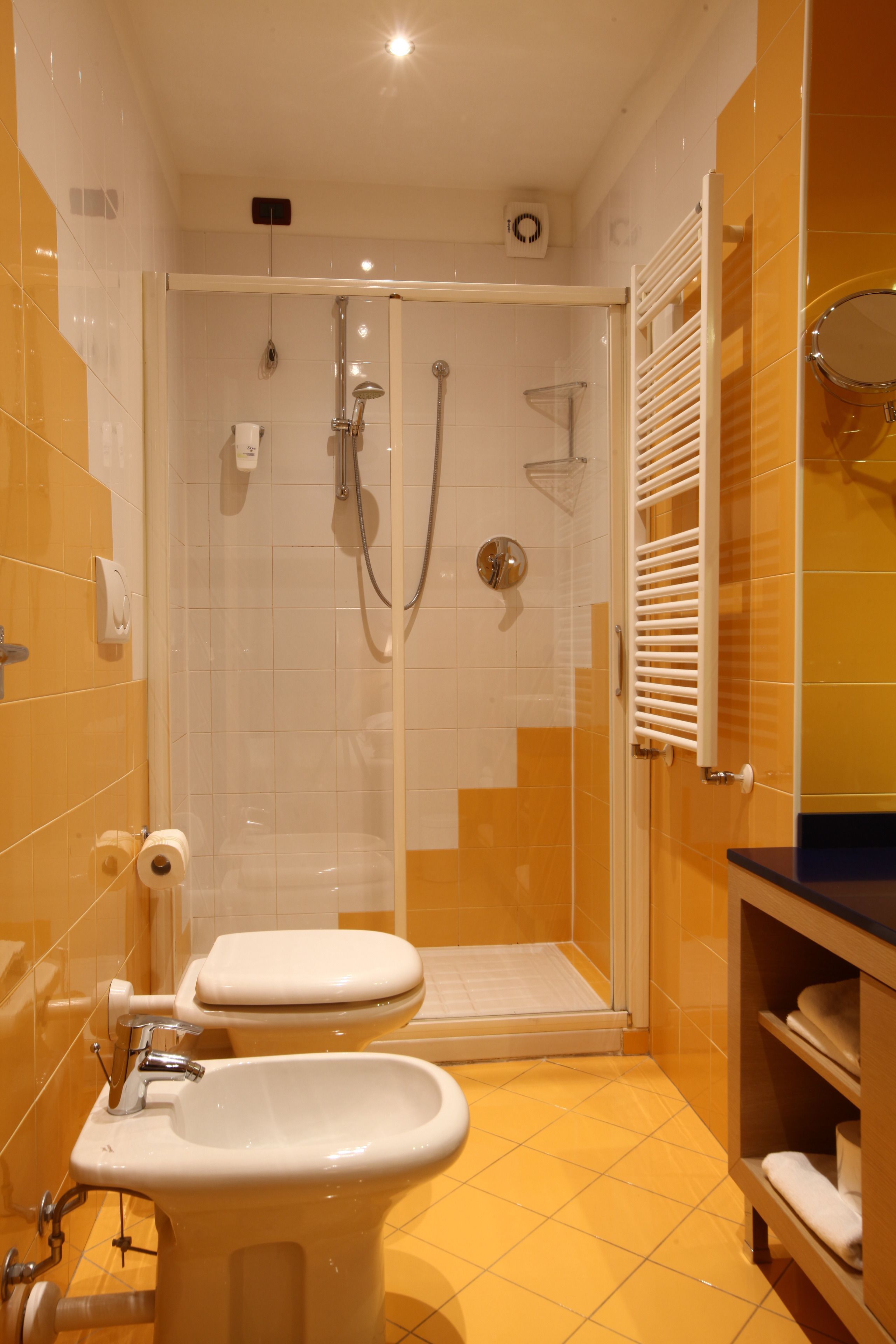 A bathroom with a shower, toilet, bidet, and a sink.