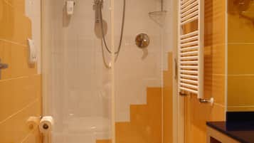 A bathroom with a shower, toilet, bidet, and a sink.