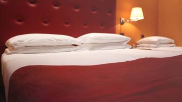 A neatly made bed with white linens and a red headboard.