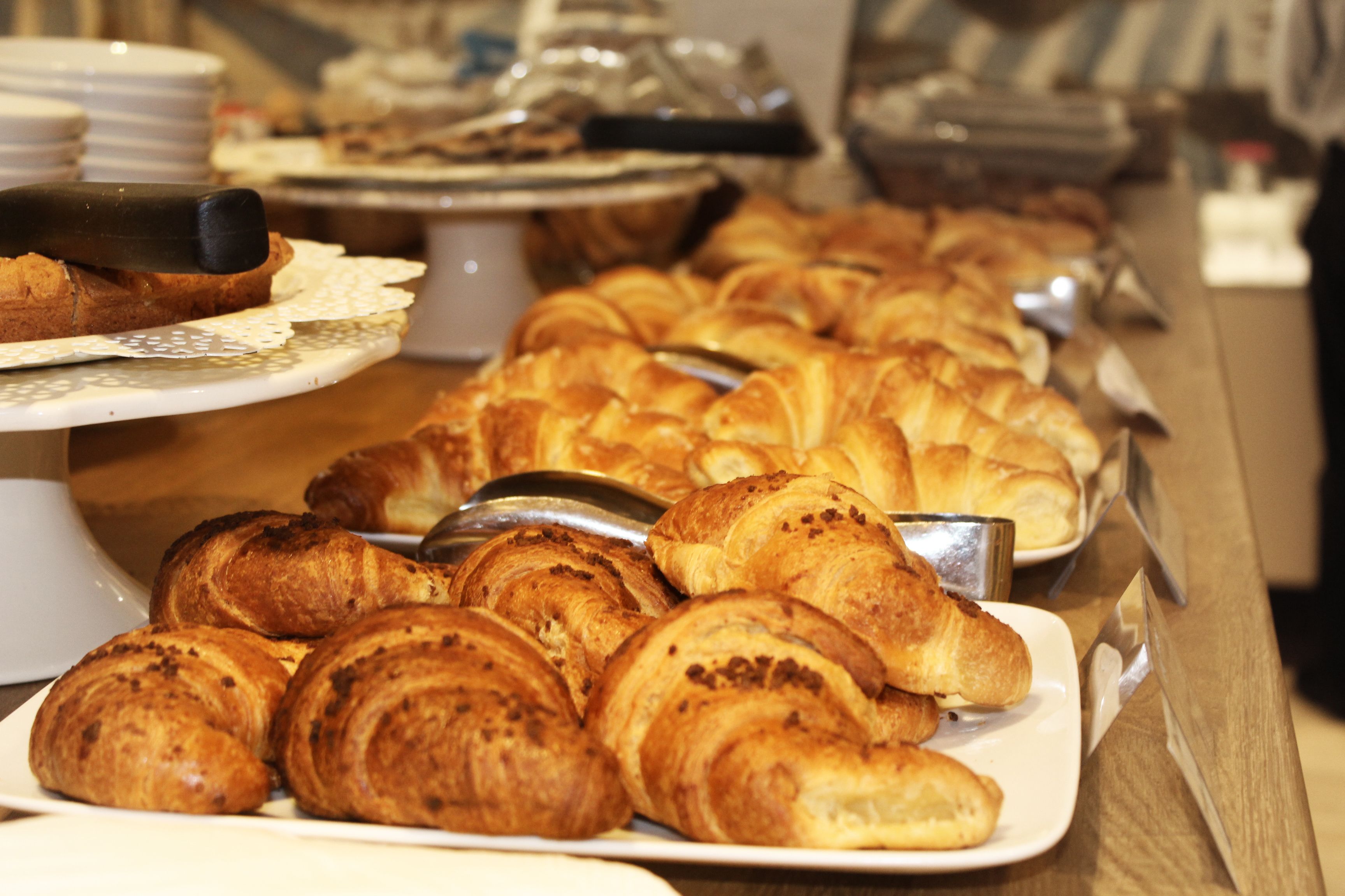 Ein Buffet mit verschiedenen Backwaren und Brot, darunter Croissants und Baguettes.