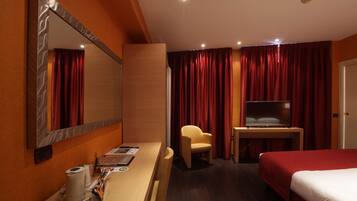 Une chambre d’hôtel comprenant un lit, un bureau avec une chaise, une télévision et un miroir.