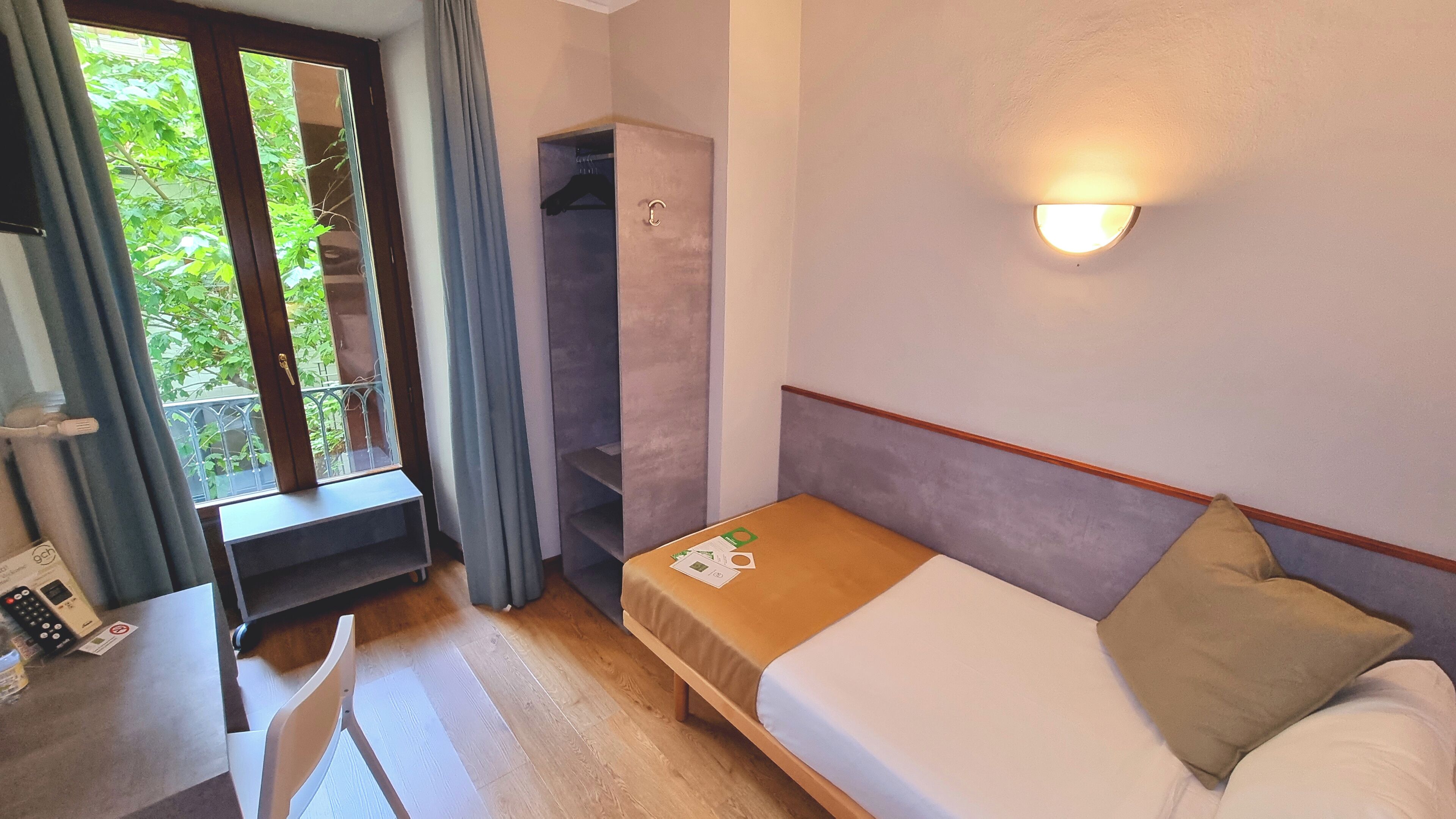 A compact hotel room with a single bed, a desk, and a wardrobe.