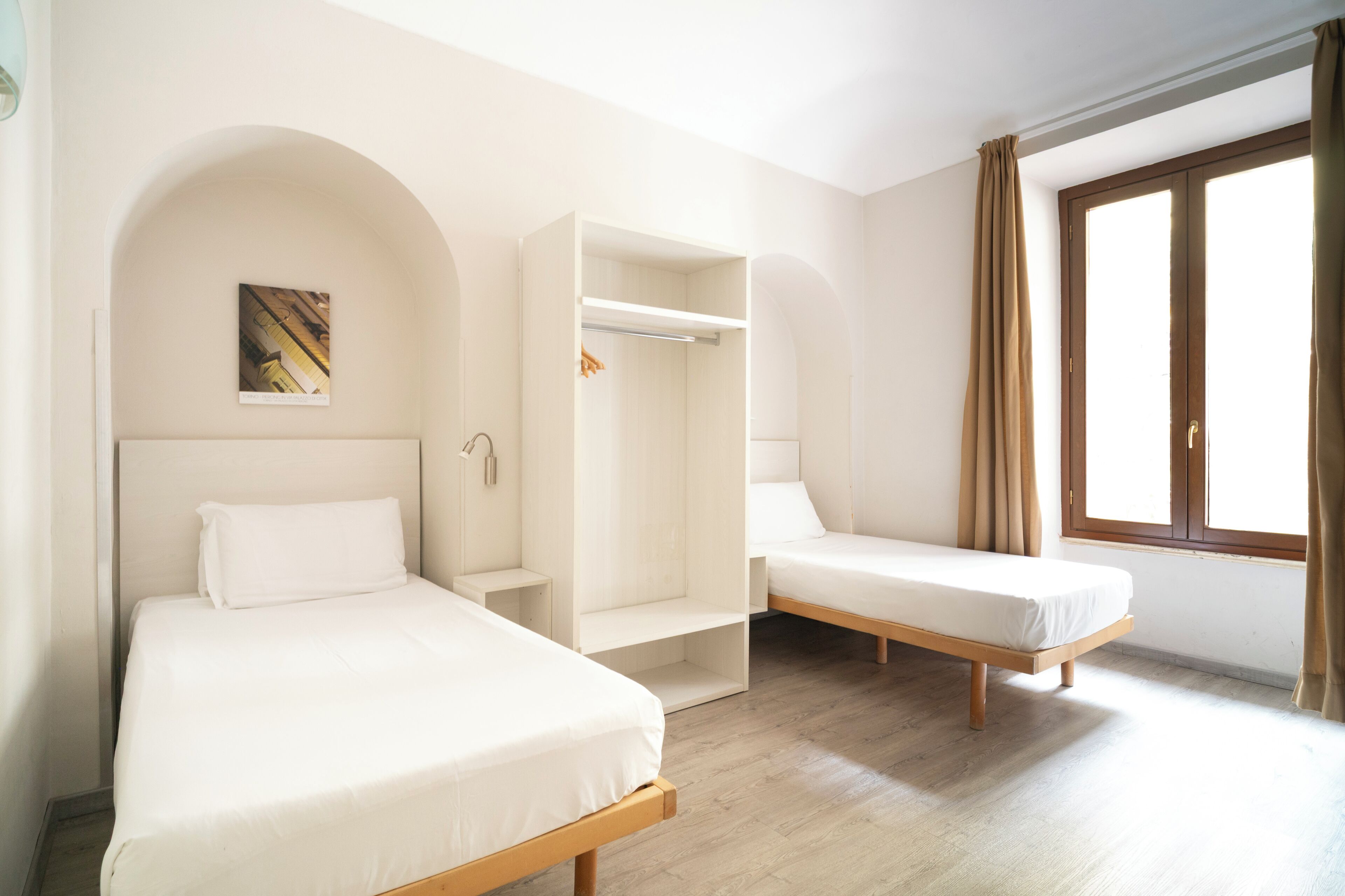 A room with two beds, a wardrobe, and a window.