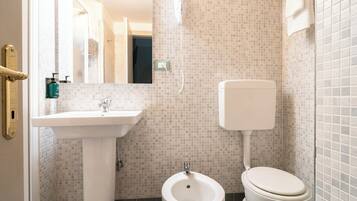 Un baño con un lavamanos blanco, un bidé y un inodoro.