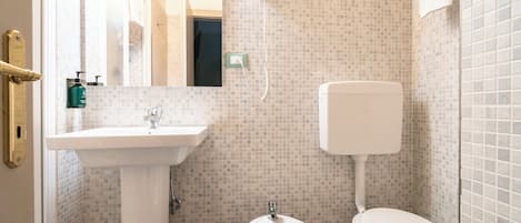 Un baño con un lavamanos blanco, un bidé y un inodoro.