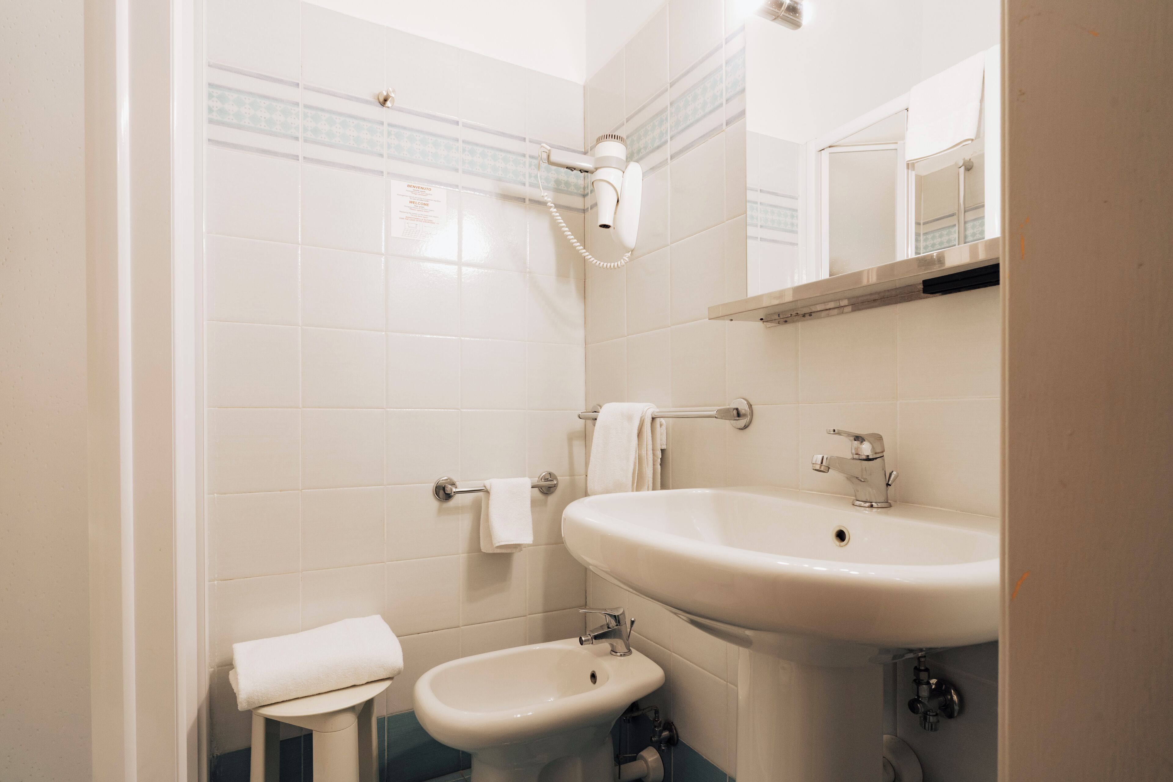 Une salle de bain avec un lavabo blanc, un bidet et un porte-serviettes.