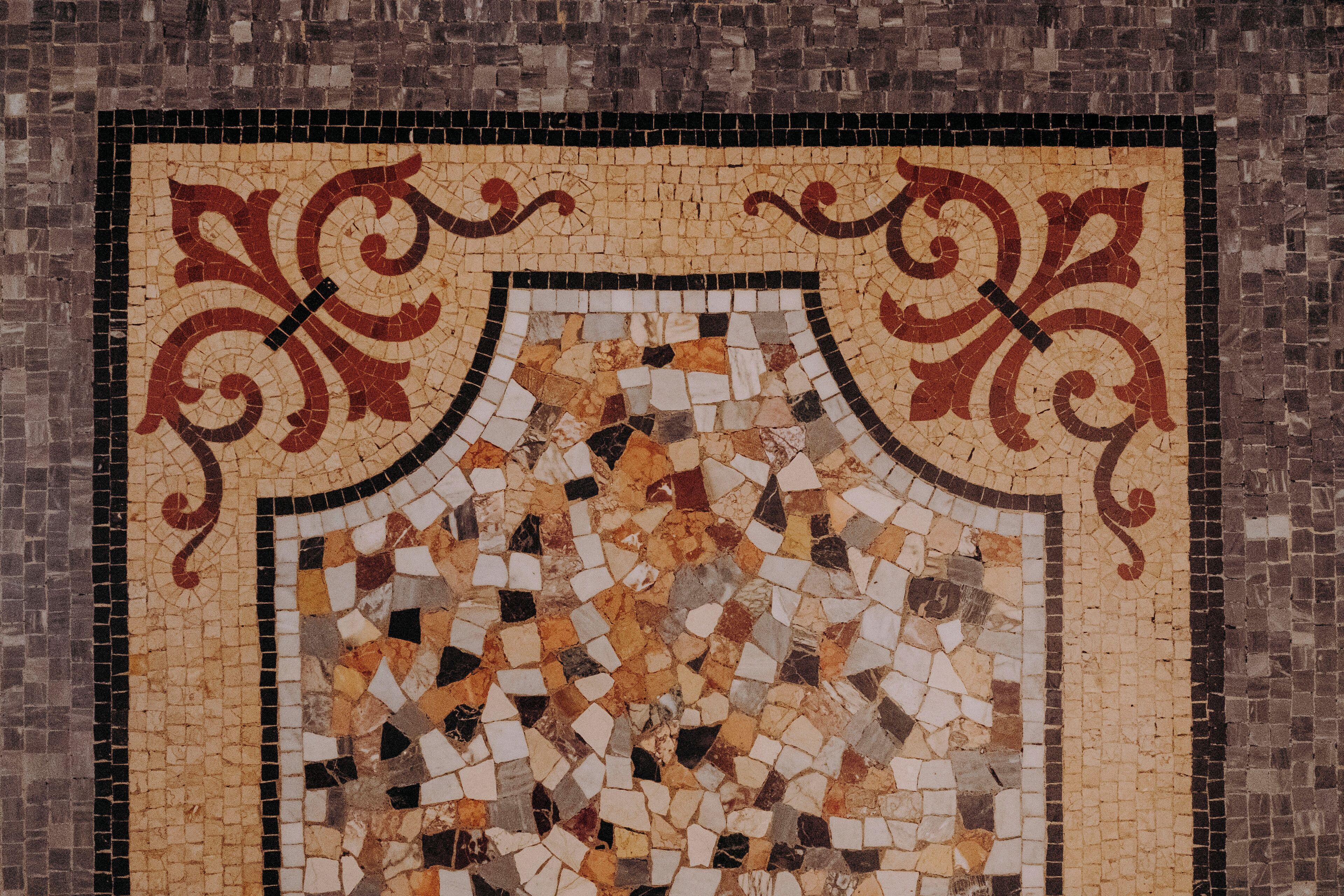 A mosaic with a shield-like design, featuring a mix of geometric and organic shapes.