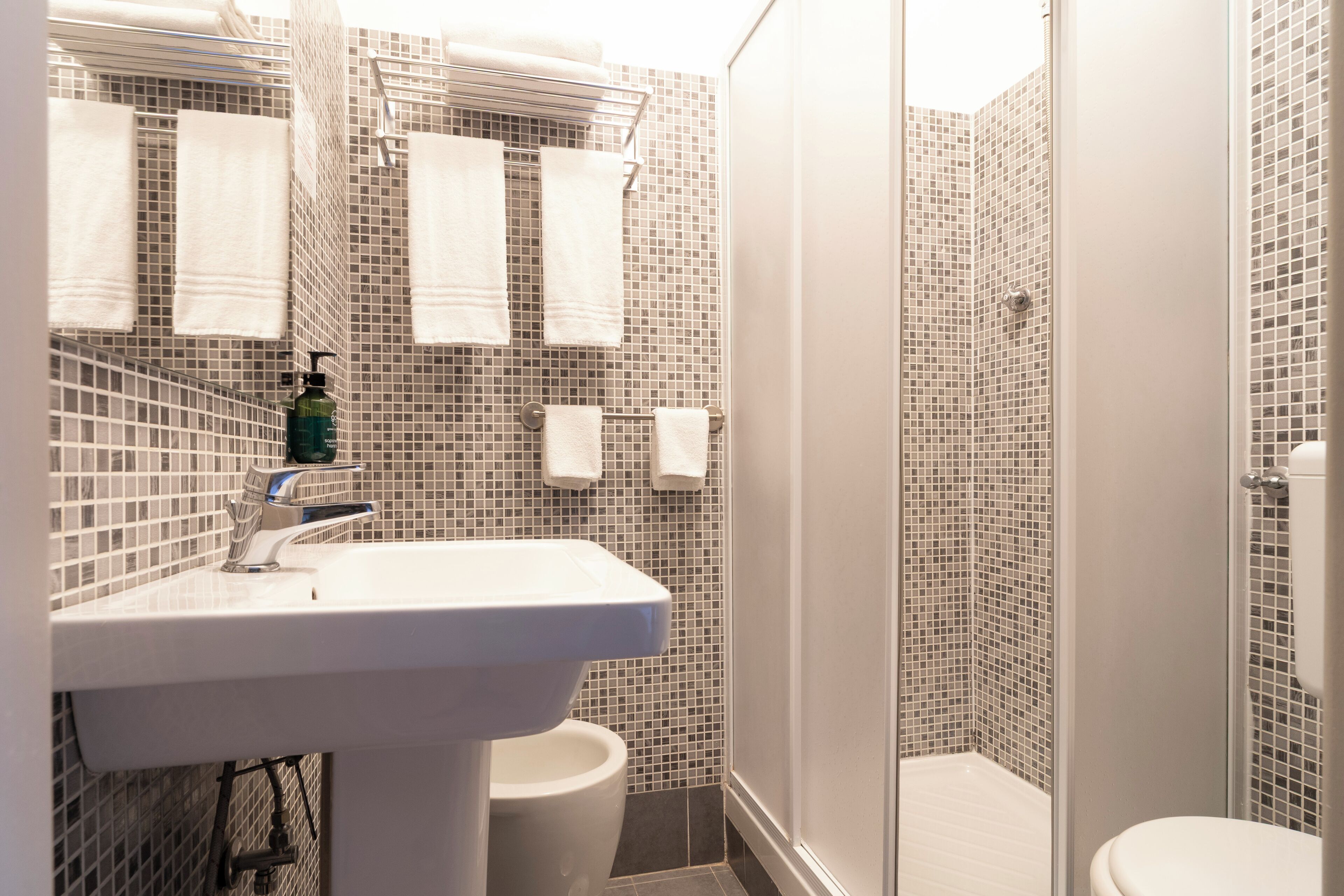 A bathroom with a white sink, a toilet, and a shower area with tiled walls.
