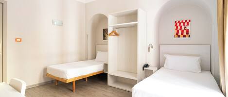 A modern hotel room with two single beds, a walk-in closet, and a wooden floor.