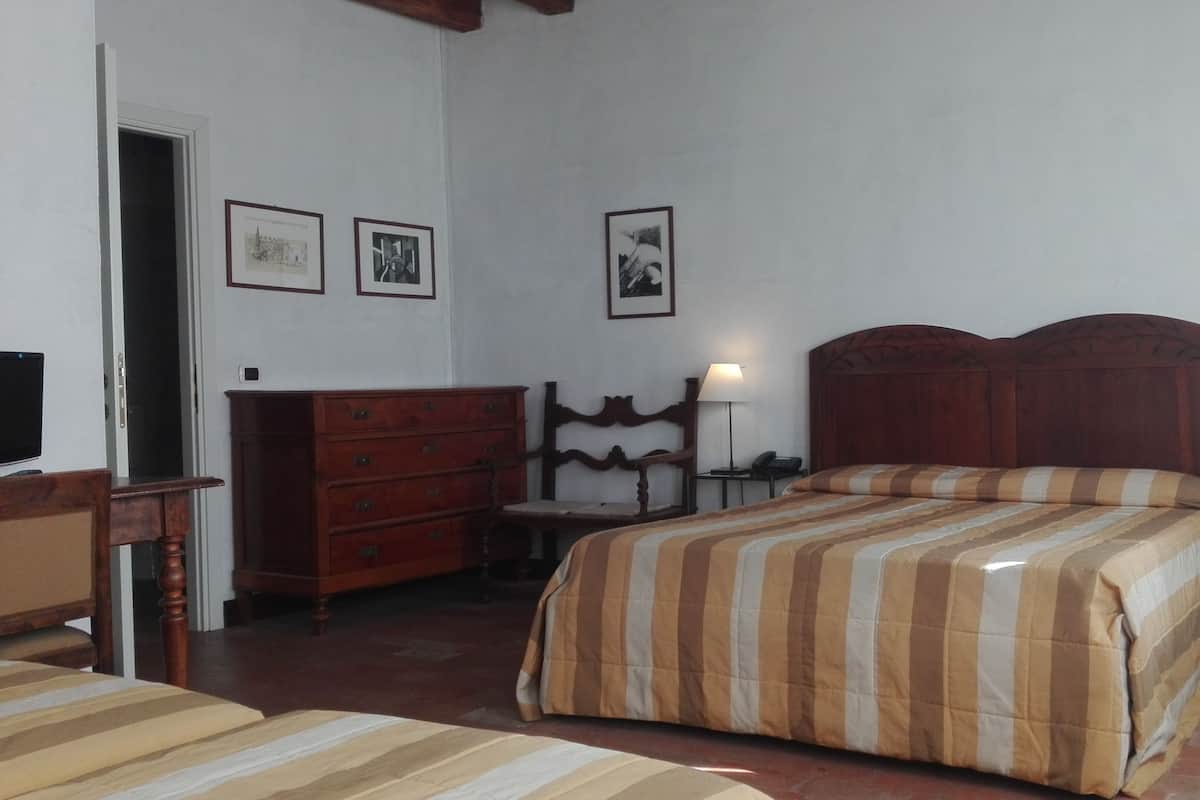 A bedroom with a bed, wooden dresser, chair, and bedside tables.