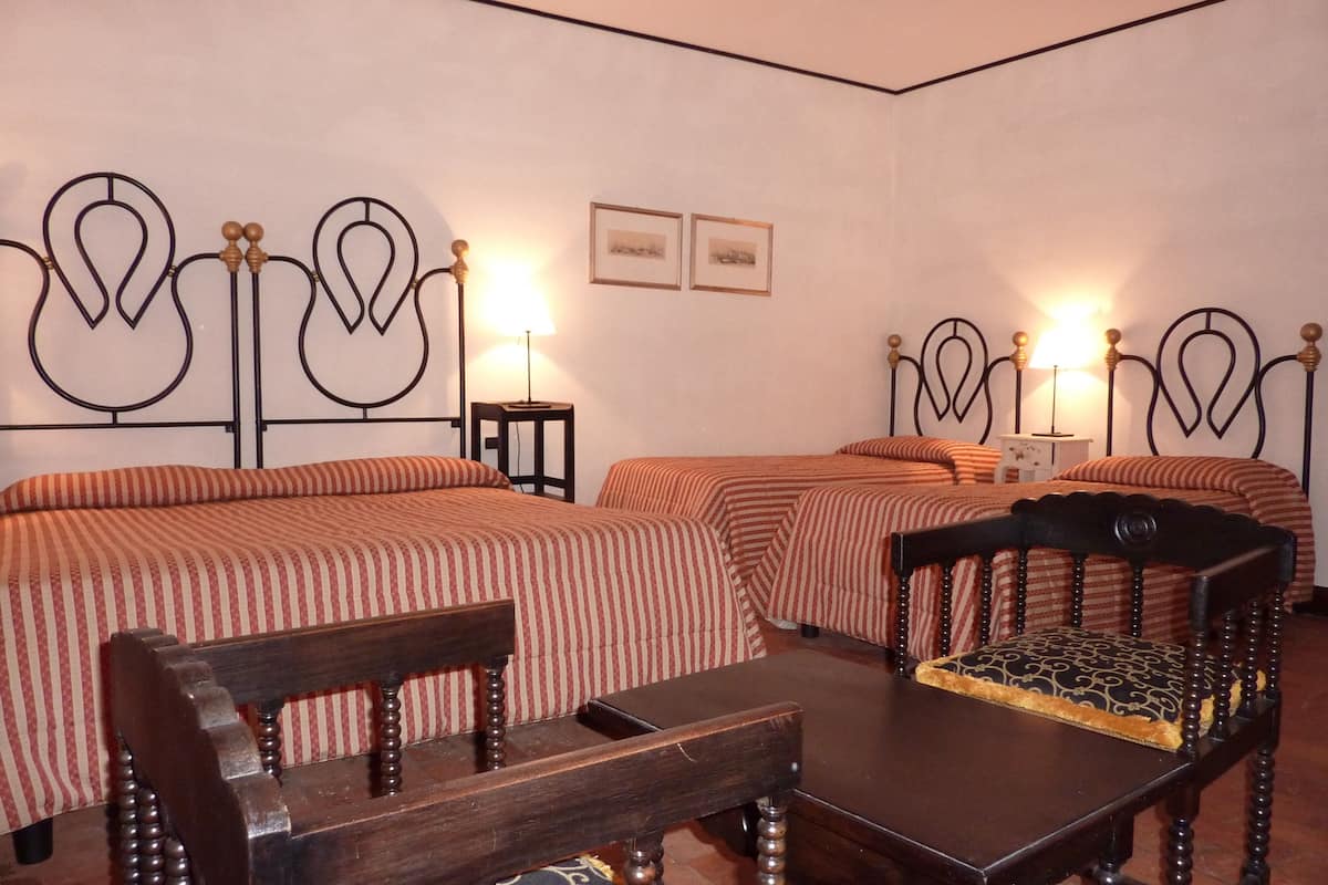 A hotel room with two beds, a wooden chair, a small table, and two bedside lamps.
