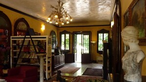 A cozy living room with a fireplace, bookshelves, a red armchair, and a statue. - Villa Alberti Hotel (Mira)