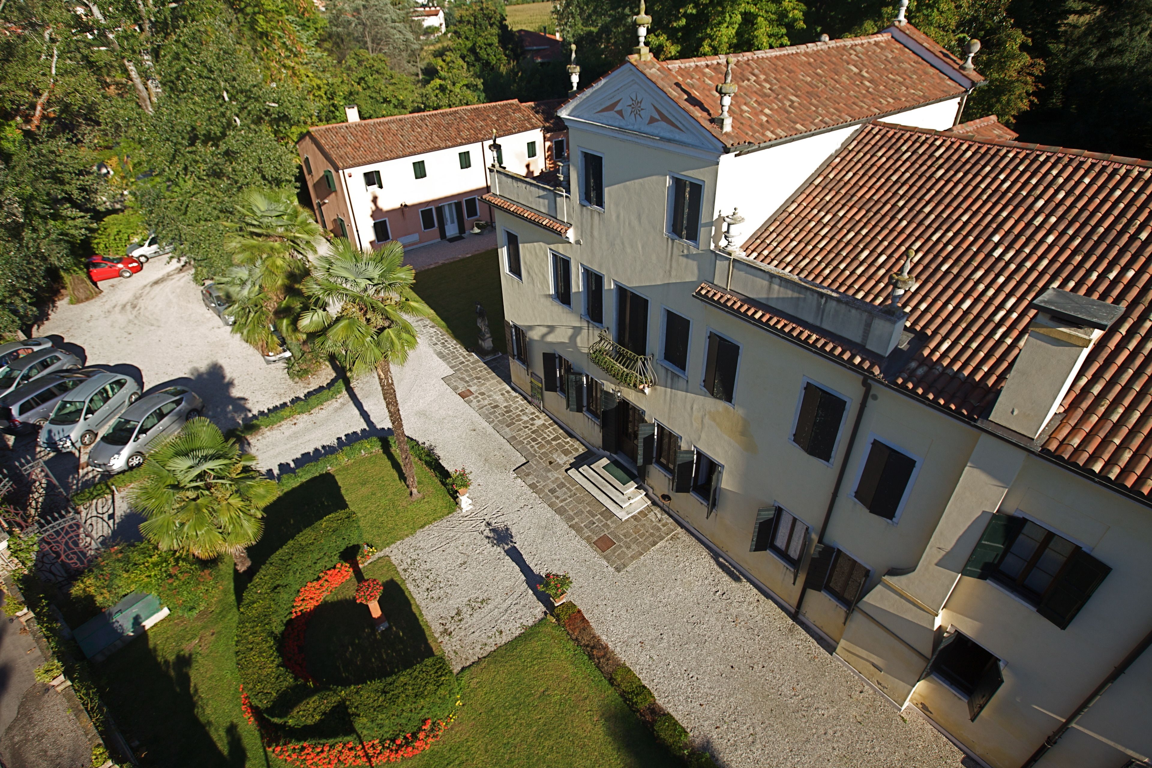 A courtyard with a statue, a well-maintained garden, and a building with a tiled roof.