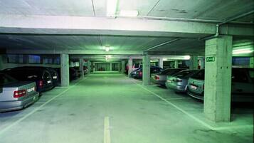 A multi-level parking garage with concrete pillars and green lighting.