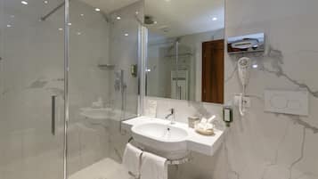 Un bagno moderno con doccia vetro, lavabo bianco e specchio con asciugacapelli integrato.