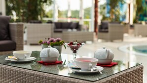 A glass-top table with tea sets and a bowl of cherries in a hotel lobby. - Hotel Terme Millepini (Montegrotto Terme)