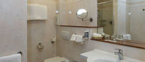 A bathroom with a toilet, bidet, sink, and a mirror.