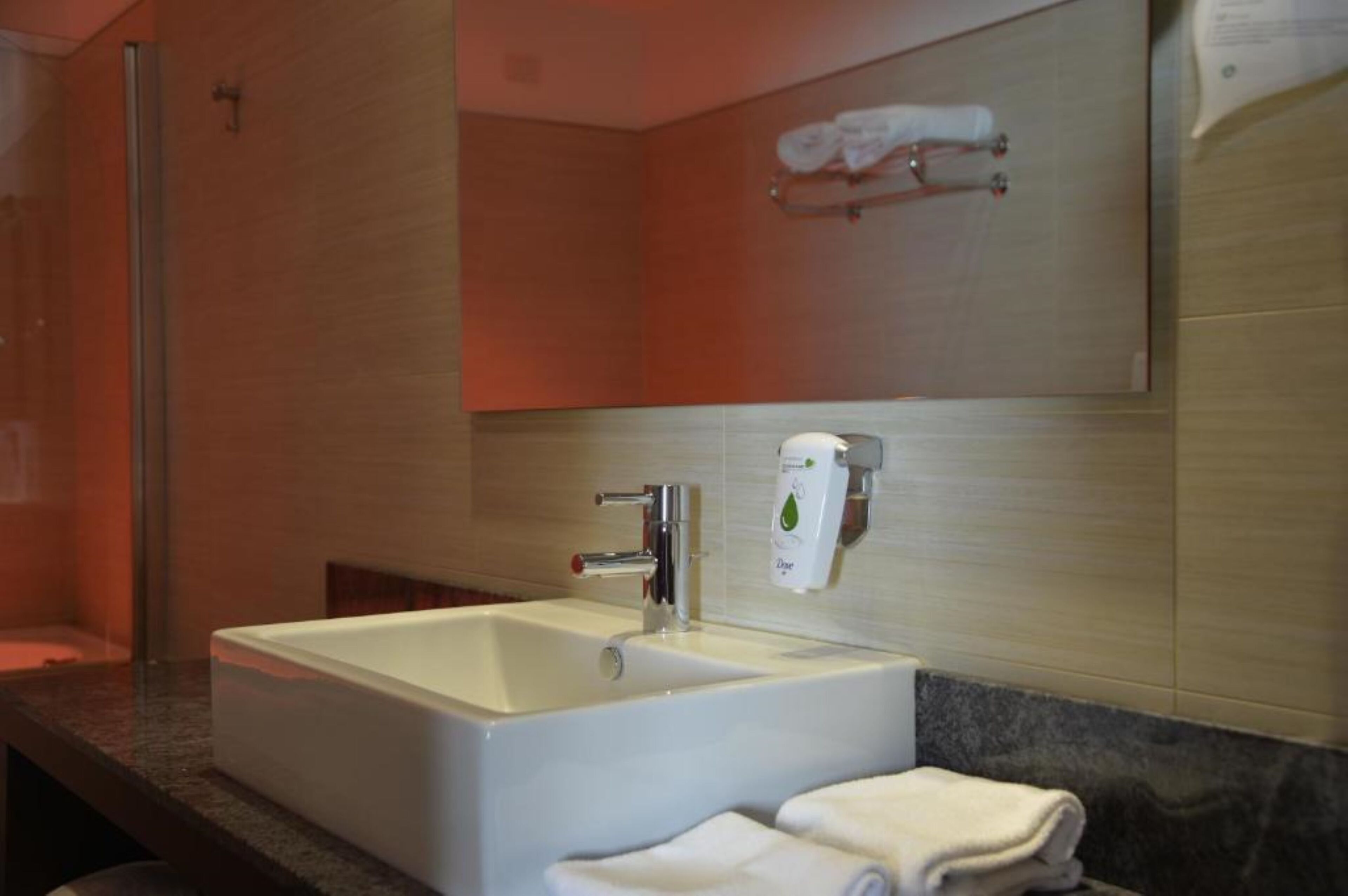 Un baño de hotel con una bañera grande, un lavabo y un espejo.
