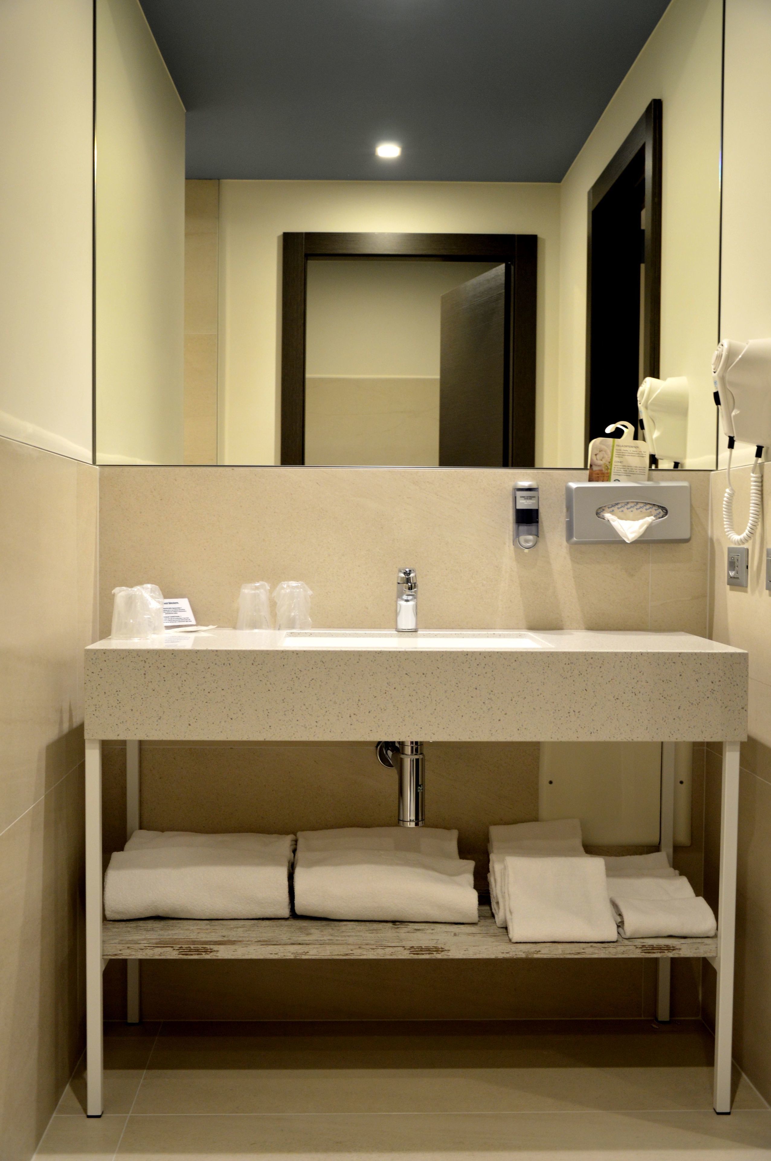 A modern bathroom with a sink, mirror, towel rack, and a hairdryer.