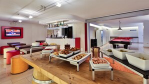 Un espace de détente moderne comprenant une table de billard, différents buffets et un écran de télévision.