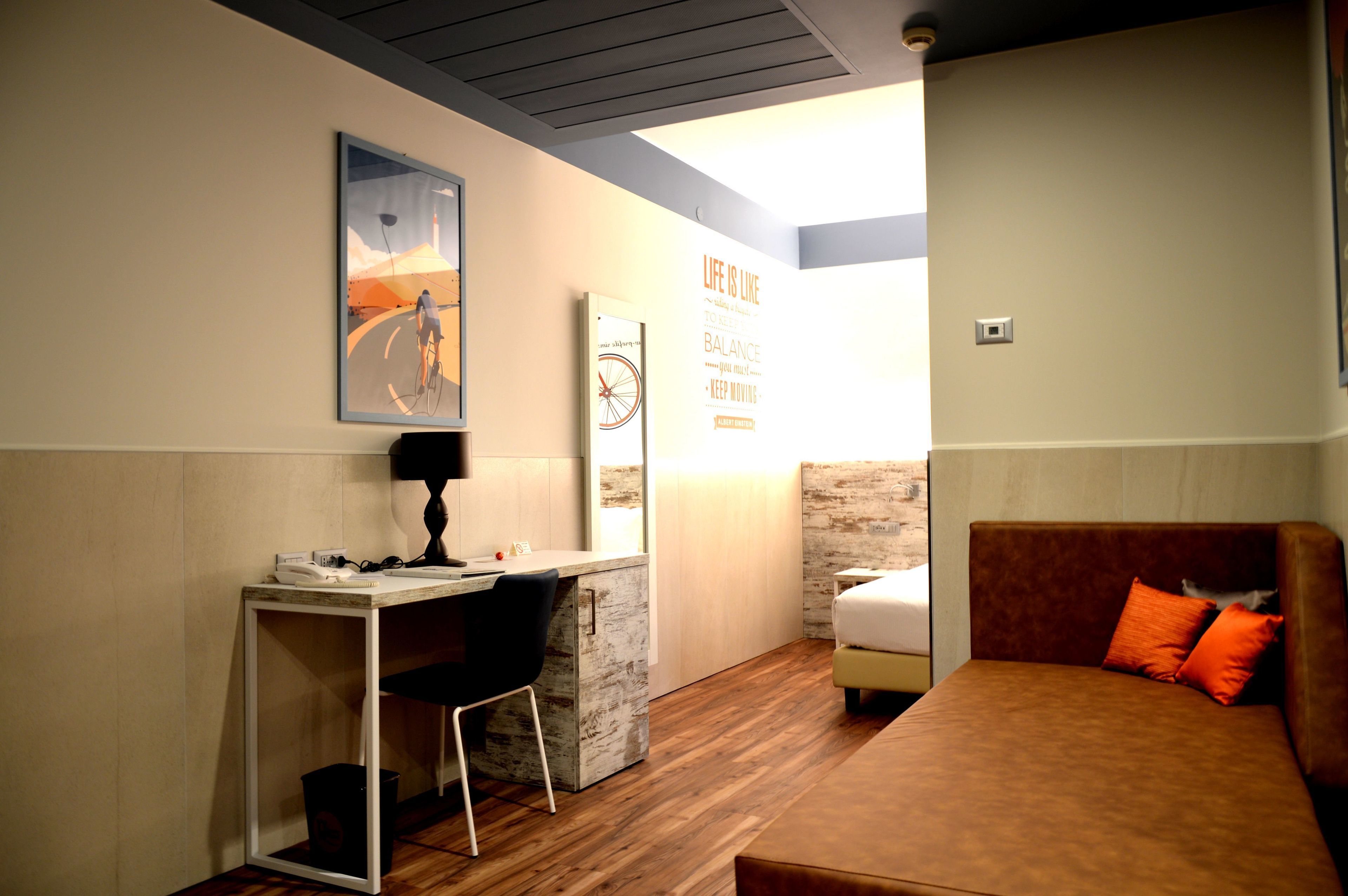 A compact room with a desk, a bed, and a wall-mounted artwork.