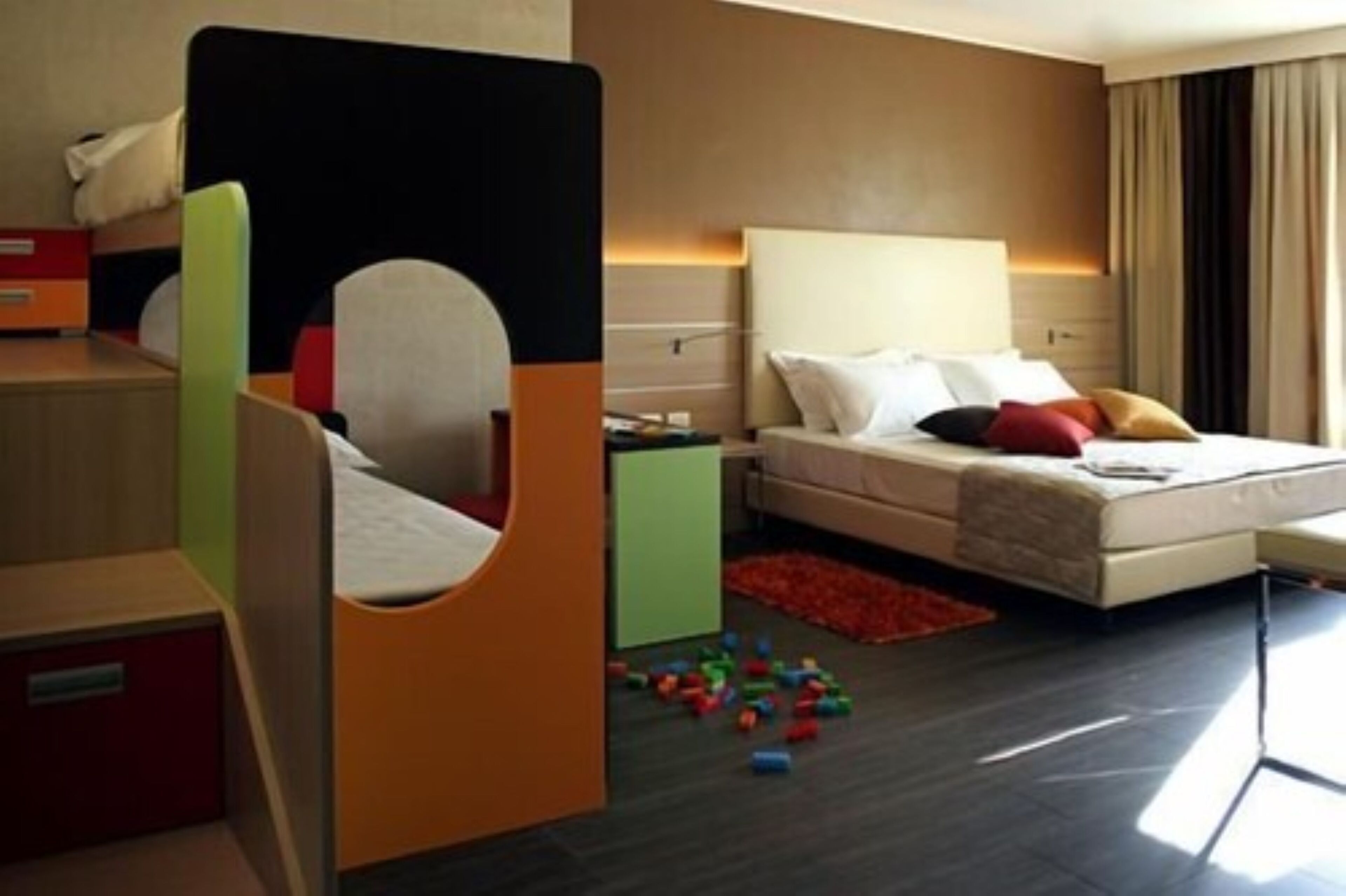A hotel room with a bed, a desk, and a colorful play area.