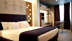 Une chambre d’hôtel avec un grand lit, une coiffeuse avec un miroir et une petite table avec des chaises.